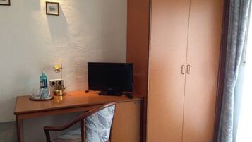A room with a wooden desk, a television, a chair, and a wardrobe.