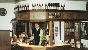 Eine Bar mit Holztresen und Regalen voller Flaschen.