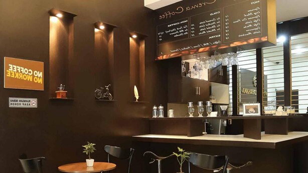 Een café met een krijtbordmenu, tafels met stoelen en een rookverbod.