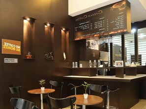 A café with a chalkboard menu, tables with chairs, and a sign prohibiting smoking.