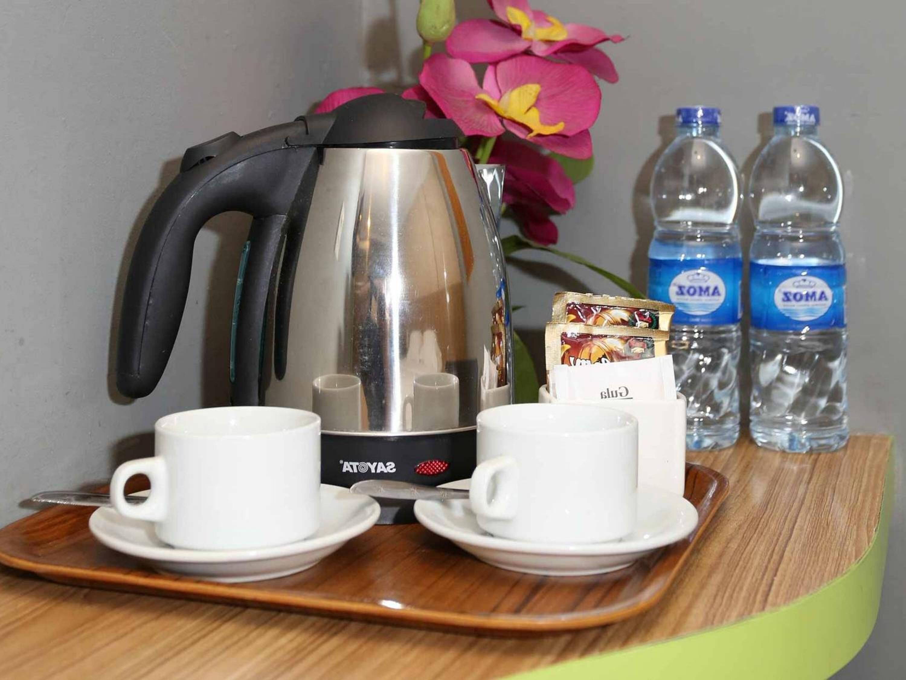 Un plateau contenant une cafetière, deux tasses, une boîte de collations et deux bouteilles d’eau.