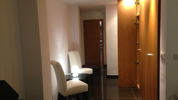 Un pasillo con una mesa de comedor y sillas, una puerta de madera y una lámpara.