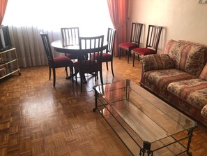 A living room with a glass coffee table, a sofa, and a dining area with chairs. - SI Rooms Puerta del Sol (Castelló de la Plana)