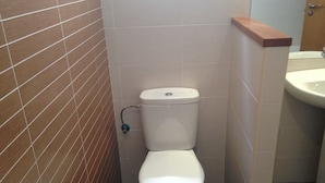 Un baño pequeño con inodoro, lavamanos y paredes de azulejos.