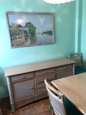 A room with a dining table, a chair, a cabinet, and a framed painting on the wall. - SI Rooms Puerta del Sol (Castelló de la Plana)