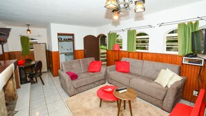 Una sala de estar con dos sofás, una mesa de centro, un televisor y un comedor con mesa y sillas.