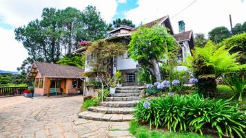Uma casa com um caminho de pedra que leva à entrada, rodeada por vegetação exuberante e um pequeno jardim.