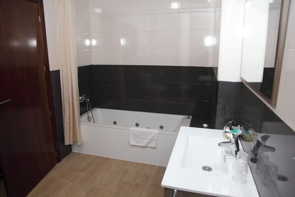 A bathroom with a bathtub, a sink, and a mirror.