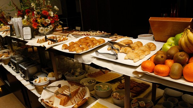Un buffet proposant une variété d’aliments, notamment des fruits, des pâtisseries et du pain.