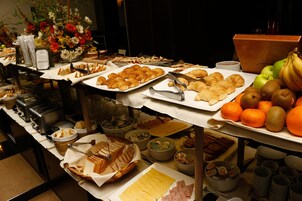 Un bufé con diferentes opciones de comida, incluyendo frutas, pasteles y pan.