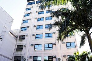 Un edificio de varios pisos con numerosas ventanas y unidades de aire acondicionado.
