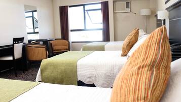 A hotel room with two beds, a desk, a chair, and a window with curtains.
