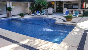 Une piscine avec des chaises longues et des plantes en pot.
