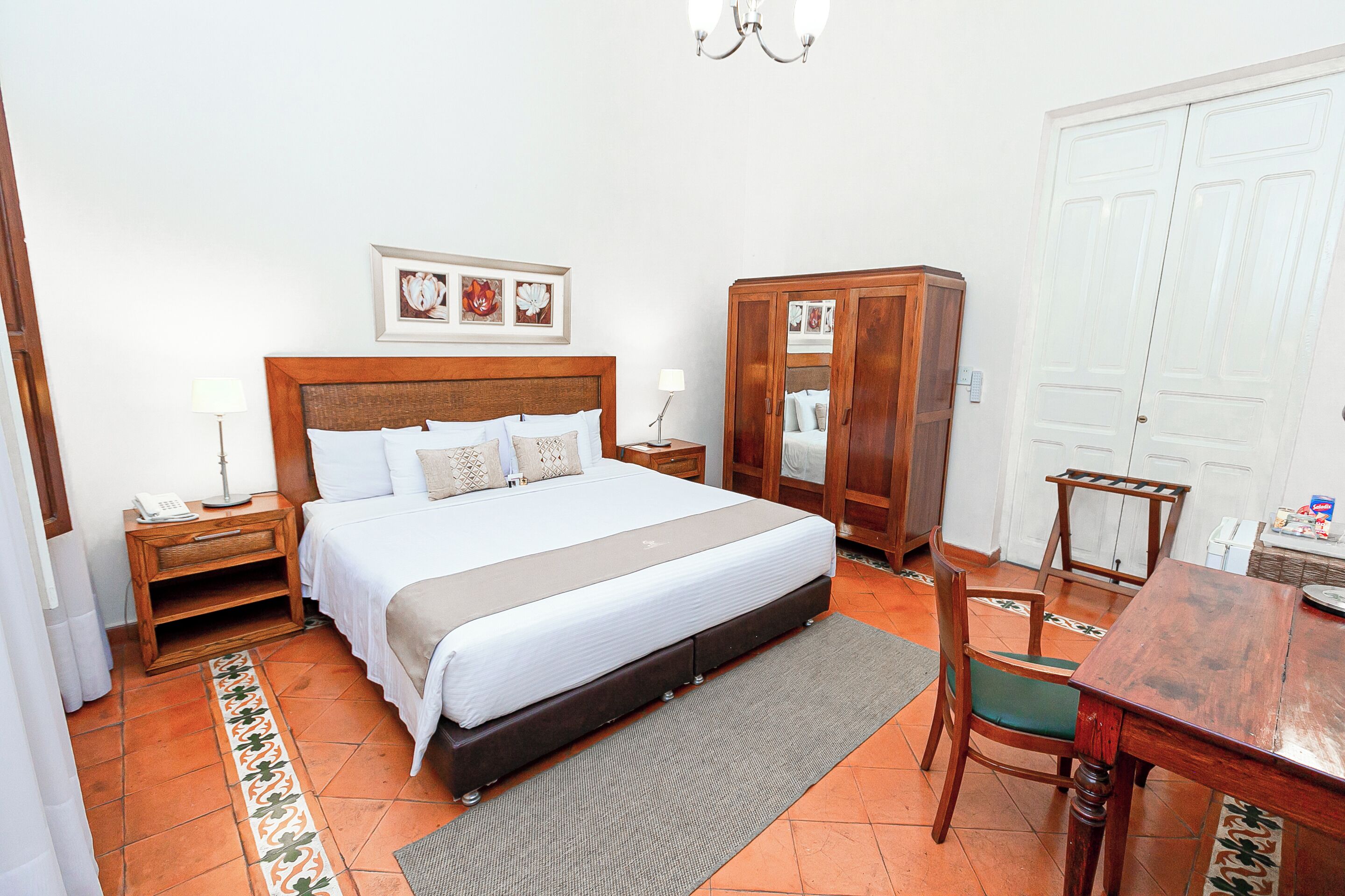 Un dormitorio con cama, mesitas de noche, armario, mesa de comedor y una silla.