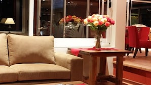 A living room with a beige sofa, a wooden coffee table with magazines, and a vase of flowers. - Rio Arriba Suites Apartments y Resto (Bella Vista)