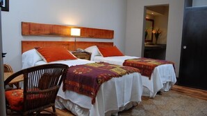A hotel room with two beds, a wooden headboard, a wicker chair, and a small table. - Rio Arriba Suites Apartments y Resto (Bella Vista)
