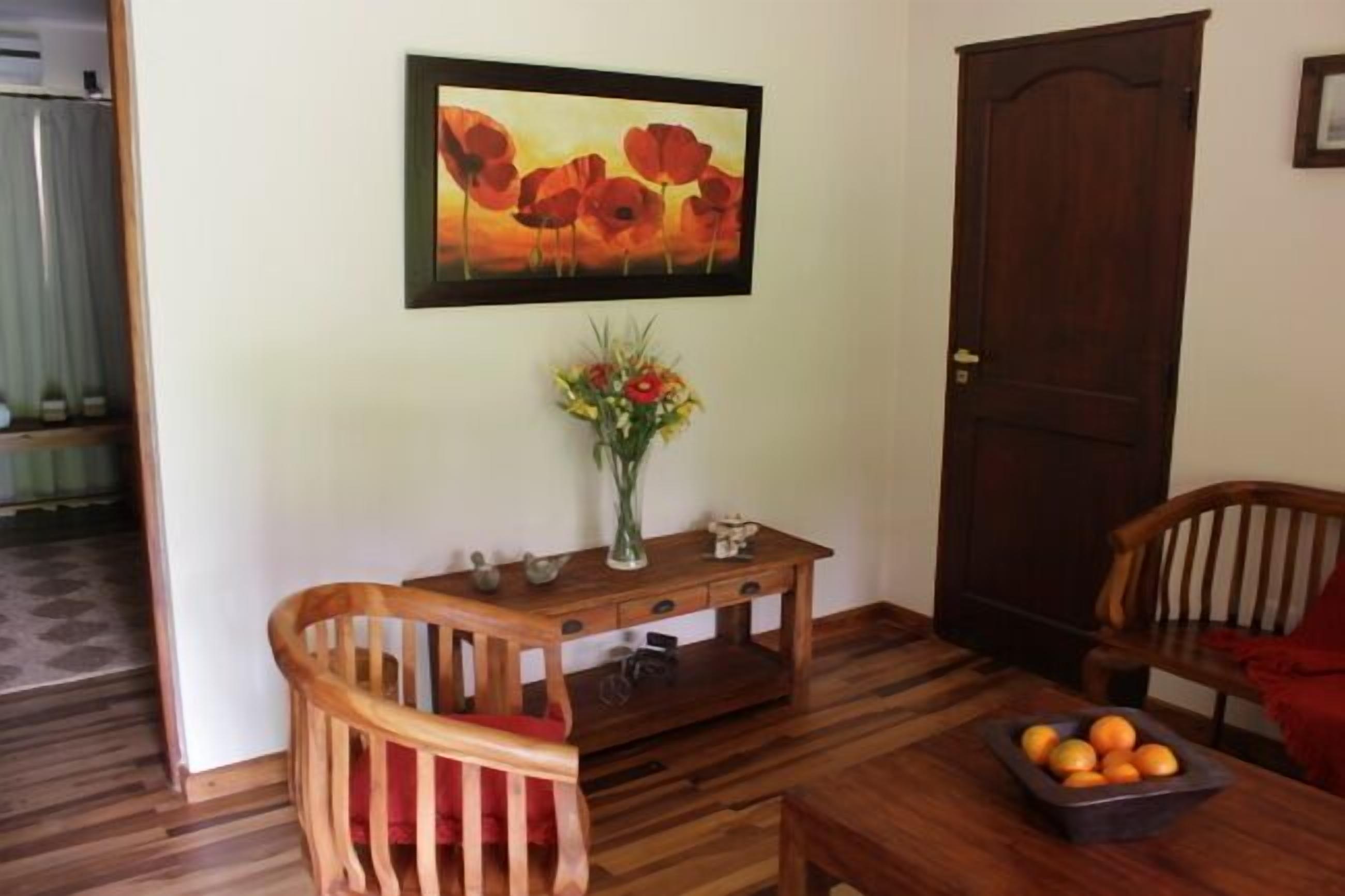 A wooden dining table with a vase of flowers and a bowl of oranges.