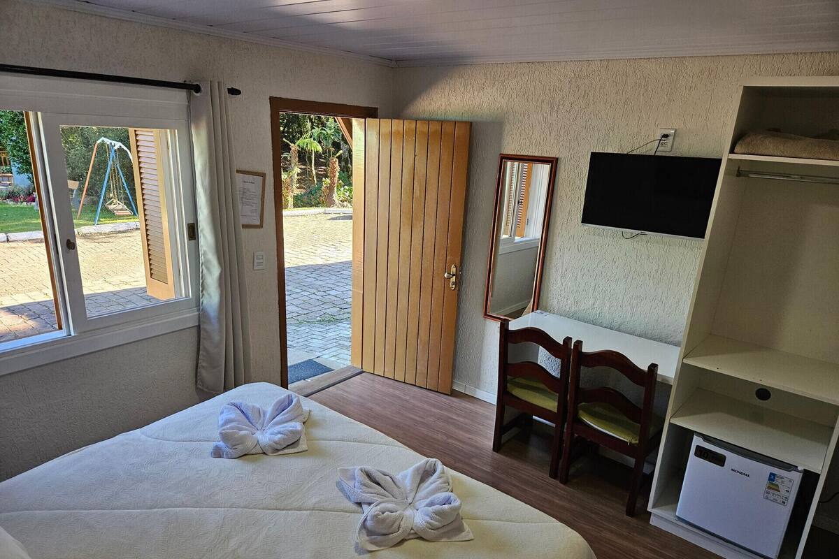 Habitación de hotel con dos camas, un escritorio, una silla, un televisor y un minibar.