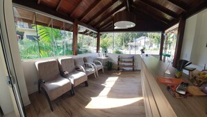 Una habitación amplia con techo de madera, zona de estar con sofás, mostrador de madera y ventanas grandes que ofrecen vistas a zonas verdes y edificios.