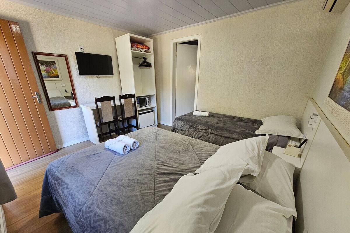 Un dormitorio con dos camas, televisión, microondas y armario.