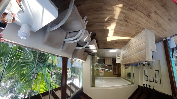 Un interior moderno con techo de madera, ventanas amplias con vistas a la vegetación y una zona de recepción con diplomas enmarcados.