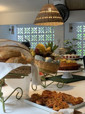 Une table de buffet proposant divers aliments, notamment du pain, des fruits et un gâteau.