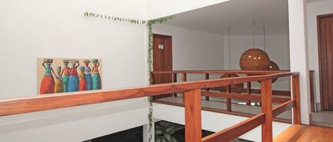 Una escalera de madera en un edificio con paredes blancas, un cuadro y una puerta.