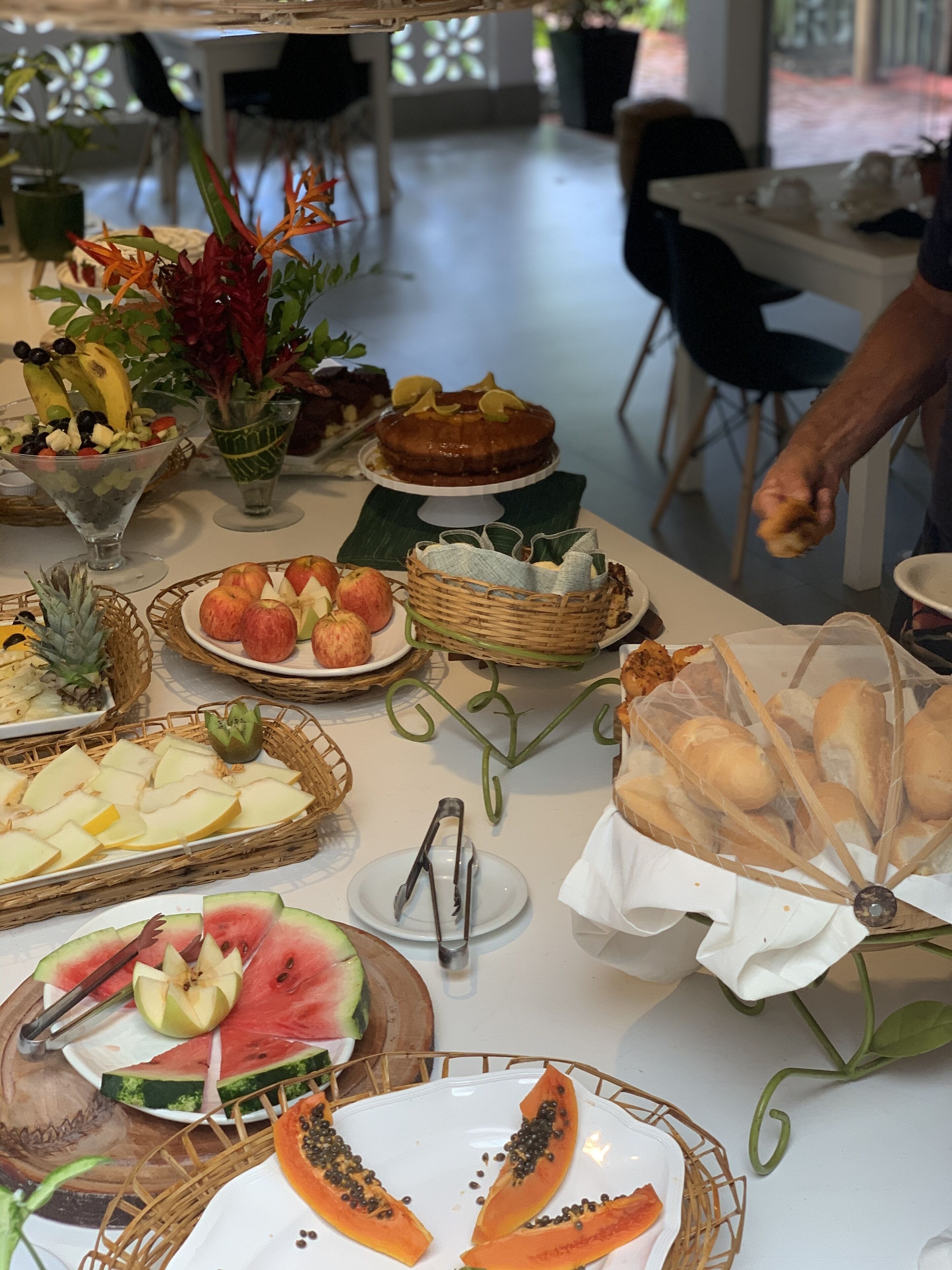 A table with various food items, including fruits, a cake, and bread.