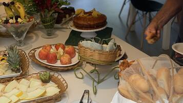 A table with various food items, including fruits, a cake, and bread.