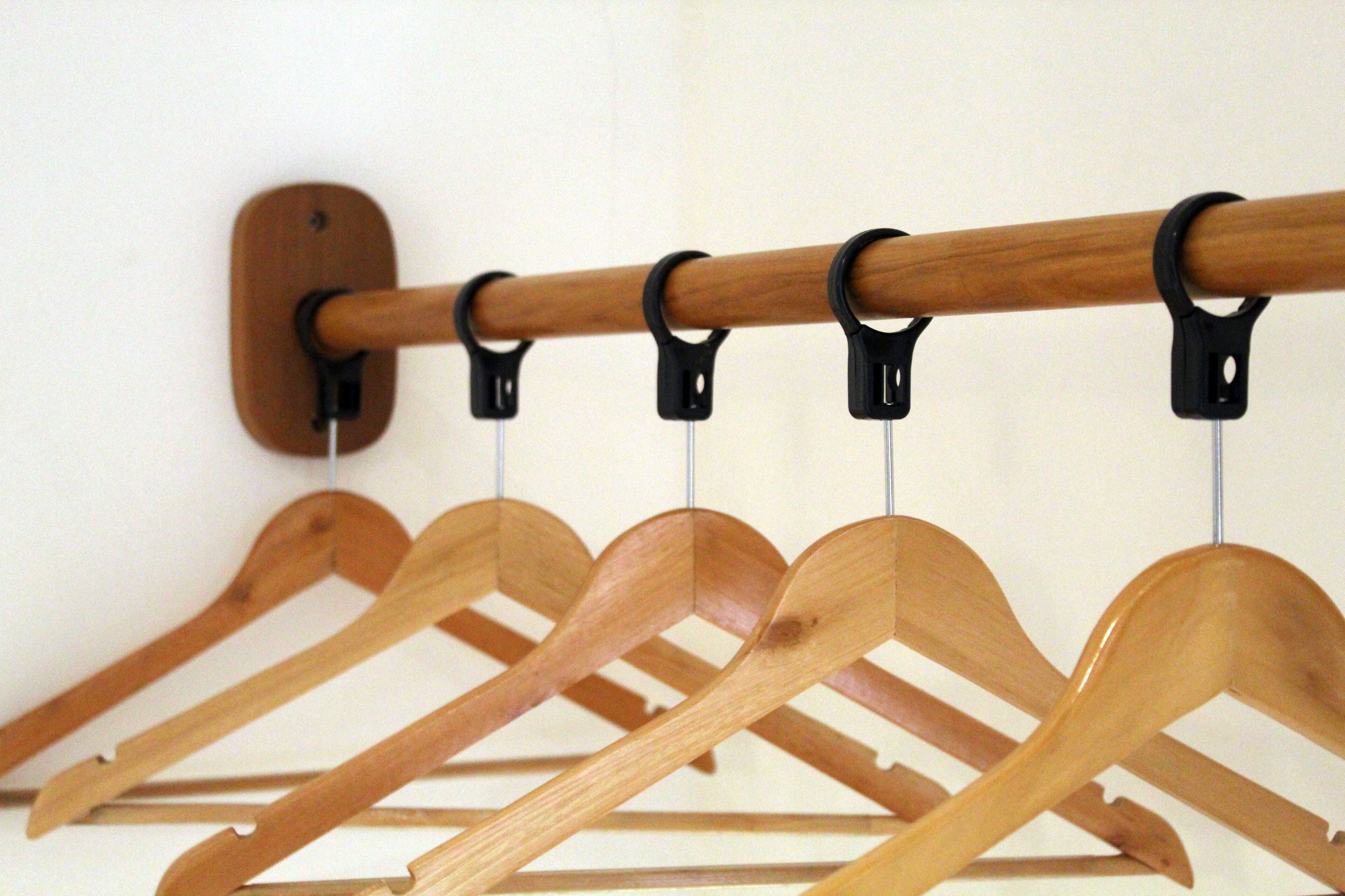 A wooden coat rack with multiple hooks against a plain wall.