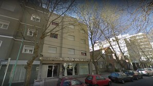 A building with a sign for 'Asociacion Obrera Minera Argentina' and a 'Hotel Espana' sign. There are parked cars in front and trees in the foreground. - Hotel Aoma Mar del Plata (Mar del Plata)