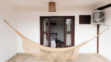 A hammock in a room with a tiled floor, a ceiling lamp, and a wall-mounted air conditioning unit.