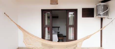 A hammock in a room with a tiled floor, a ceiling lamp, and a wall-mounted air conditioning unit.