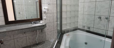 A modern bathroom with a glass-enclosed shower, a large bathtub, and a vanity with a mirror.