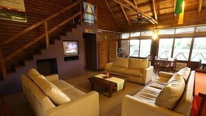 A spacious living area with a high ceiling, wooden beams, a television, and comfortable seating. - Paso del Tigre (Santa Fe)