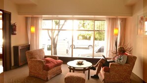 A hotel room with two patterned armchairs, a small round table, and a view of parked cars outside. - Hotel Mar Azul (Mar del Plata)