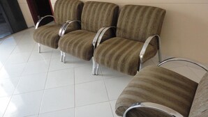 A row of four striped armchairs with metal frames, arranged in a waiting area with a tiled floor. - Hotel Premier (Campo Grande)