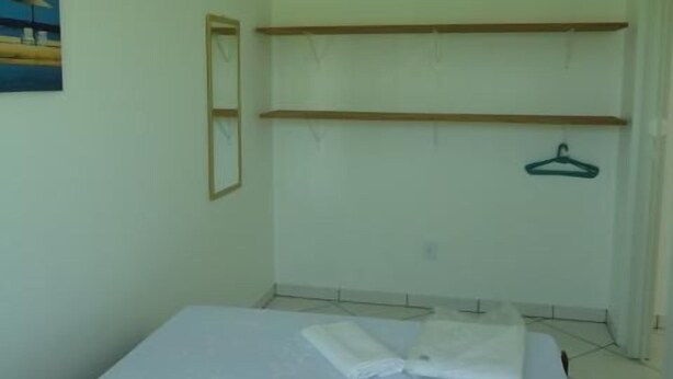 A bedroom with a bed, a hanging chair, and a painting on the wall. - Residencial Floripamar 2 (Florianópolis)