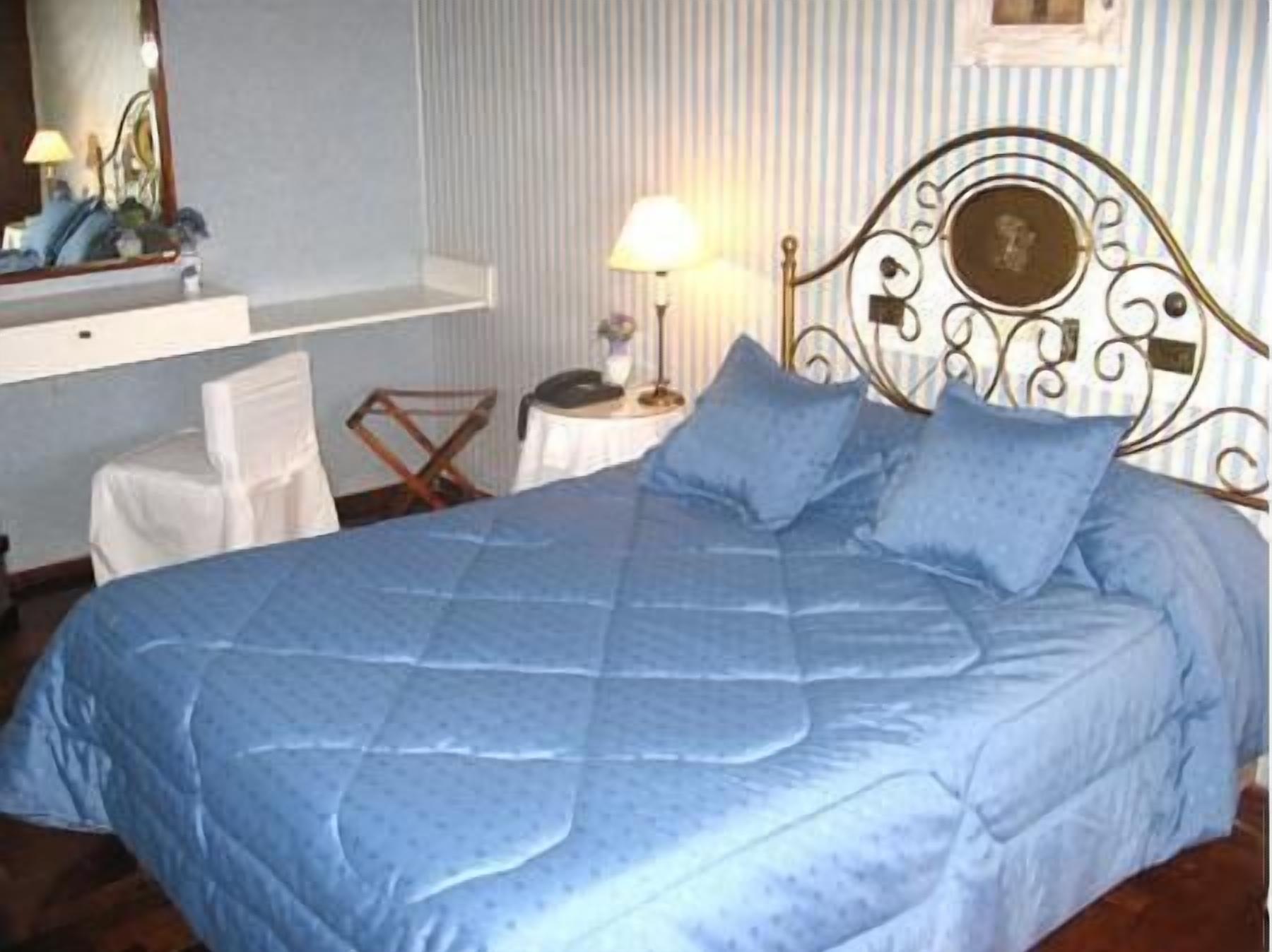 Un dormitorio con una cama grande, una mesita de noche con una lámpara y una silla.