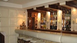 Uma área de bar com bancada de mármore, banquetes e uma variedade de garrafas e copos.