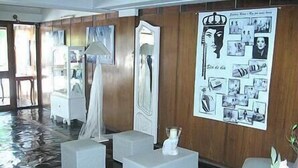 Um hall de hotel moderno com chão molhado, mobiliário branco, um espelho grande e uma parede decorada com fotografias a preto e branco.