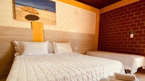 A double bed with a quilted white duvet, two pillows, and a nightstand with a white towel. - Pousada Ilha Bela (Fernando de Noronha)