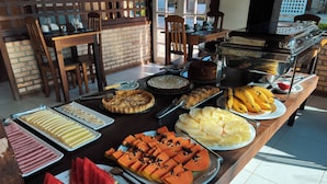 Une table de buffet proposant une variété d’aliments, notamment des fruits, des pâtisseries et un gâteau.