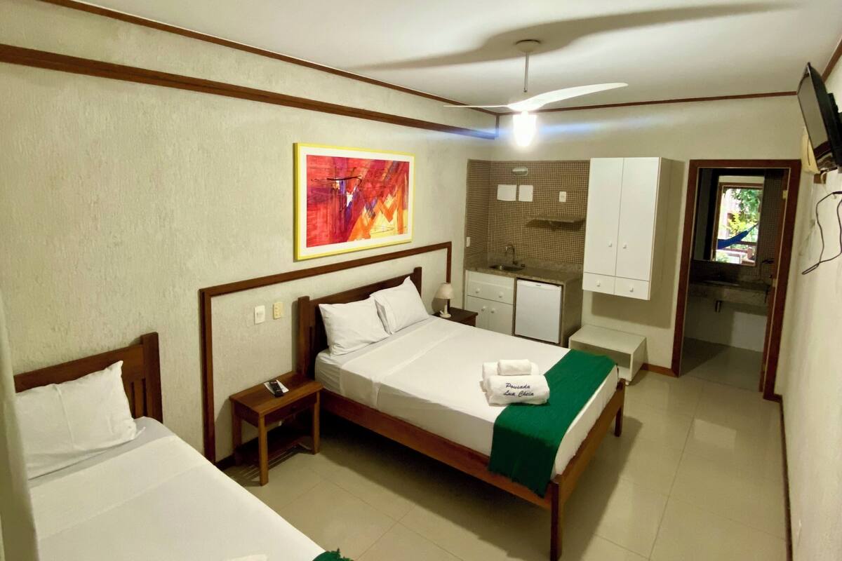 A hotel room with two beds, a small desk, a bathroom, and a TV.