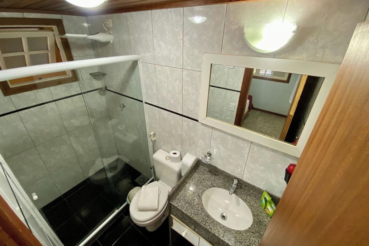 A bathroom with a shower, toilet, sink, and mirror.