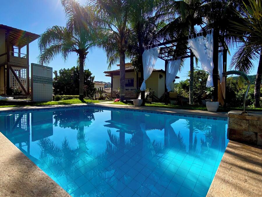 A clear blue swimming pool surrounded by palm trees and buildings.