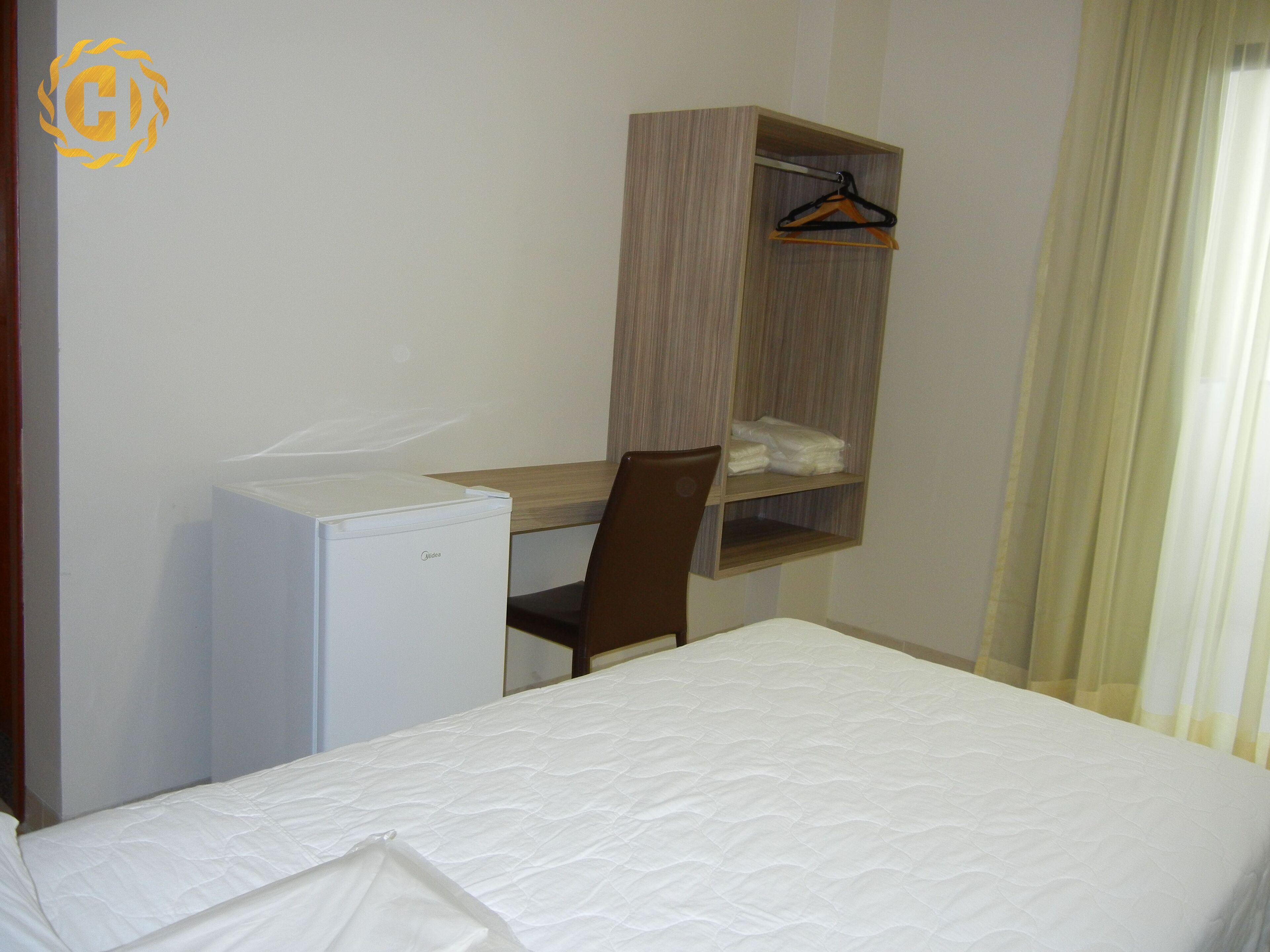 Una habitación de hotel con cama, escritorio, silla y armario.