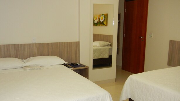 Ein Hotelzimmer mit zwei Betten, einem Nachttisch mit Fernbedienung und einem Bild an der Wand.