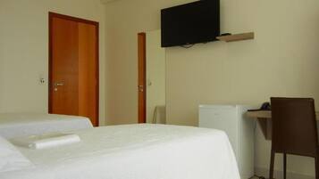 Een hotelkamer met twee bedden, een bureau met stoel, een televisie en een koelkast.