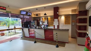 Ein Hotel-Rezeptionsbereich mit einer digitalen Uhr, einem Fernseher und einer Theke mit verschiedenen Gegenständen.
